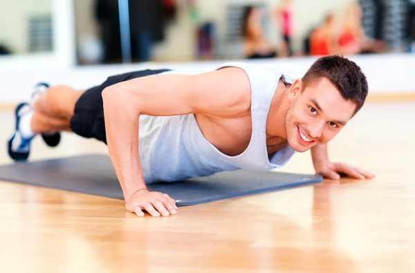 Lächelnder Mann macht Liegestütze im Fitnessstudio — Stockfoto