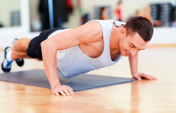 Smilende mann som tar armhevinger i gymsalen – stockfoto