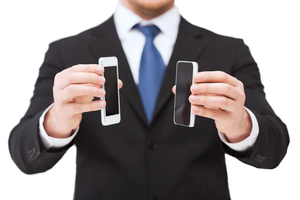 Empresario mostrando teléfonos inteligentes con pantallas en blanco — Foto de Stock