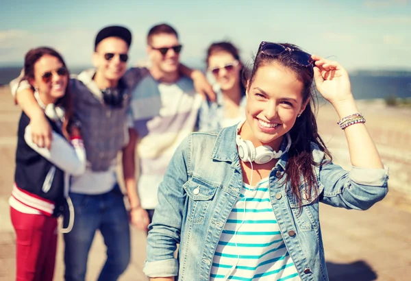 Teenage girl with headphones and friends outside — Stock Photo, Image