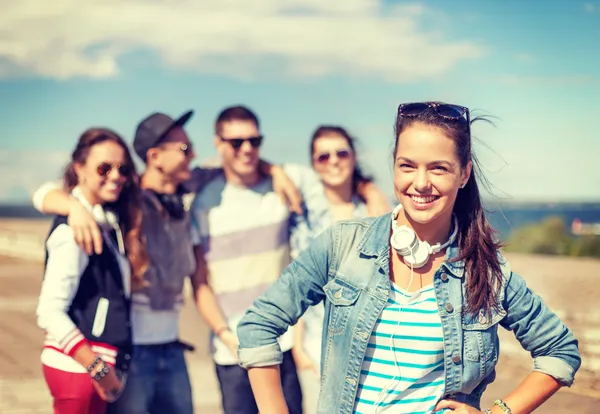 Adolescente chica con auriculares y amigos fuera — Foto de Stock