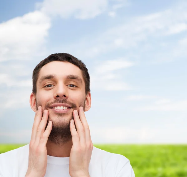 Bellissimo uomo sorridente che si tocca il viso — Foto Stock