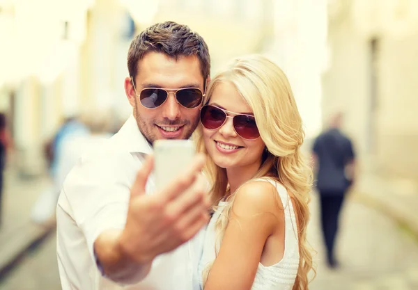 Улыбающаяся пара со смартфоном в городе — стоковое фото
