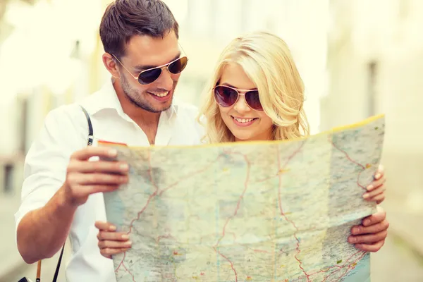 Smiling couple in sunglasses with map in the city — Stock Photo, Image