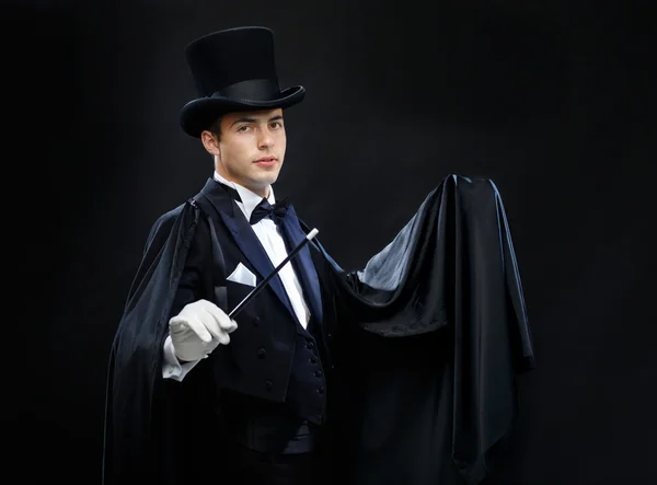 magician in top hat with magic wand showing trick