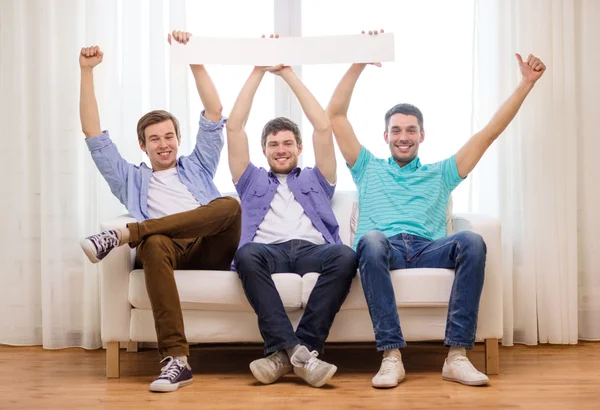 Smiling male friends holding white blank banner — Stock Photo, Image