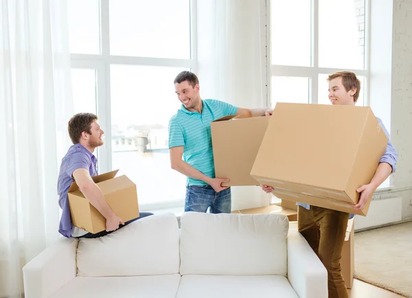 Sonriente macho amigos llevar cajas en nuevo lugar — Foto de Stock