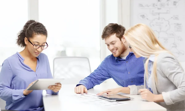 Équipe souriante avec table pc et papiers de travail — Photo