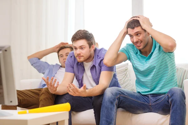 Triste macho amigos con vuvuzela viendo deportes — Foto de Stock