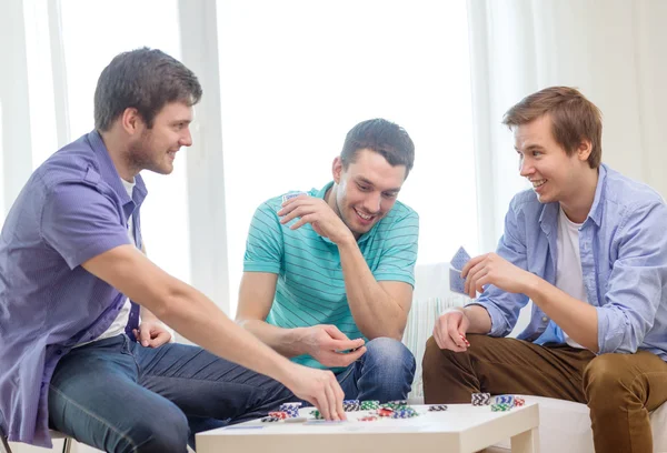 Feliz tres amigos masculinos jugando póquer en casa — Foto de Stock