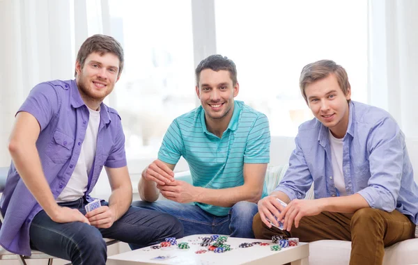 Feliz tres amigos masculinos jugando póquer en casa — Foto de Stock