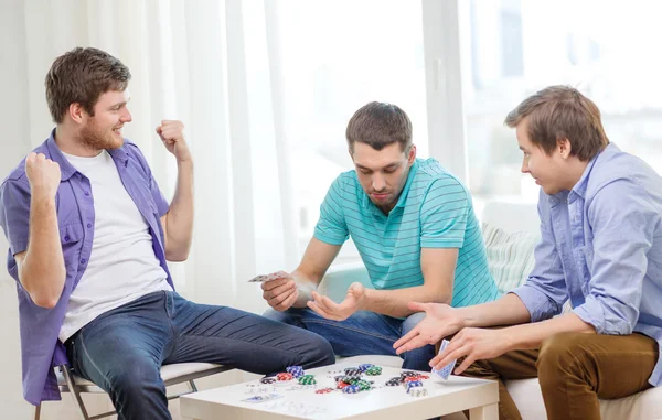 Feliz tres amigos masculinos jugando póquer en casa — Foto de Stock