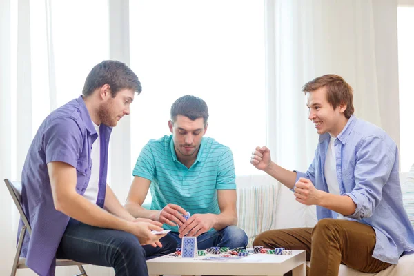 Glücklich drei männliche Freunde, die zu Hause Poker spielen — Stockfoto
