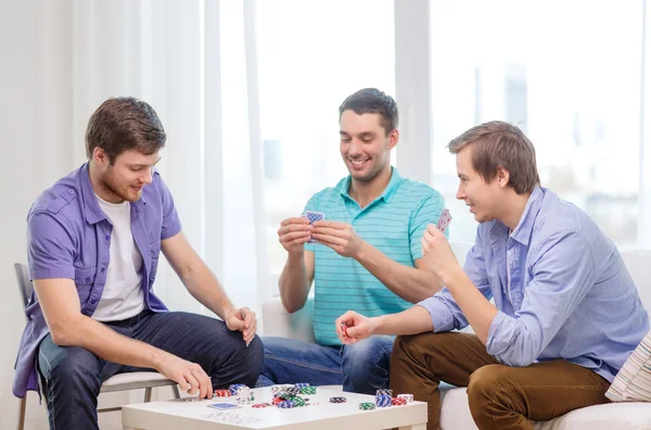 Felizes três amigos do sexo masculino jogando poker em casa Imagem De Stock