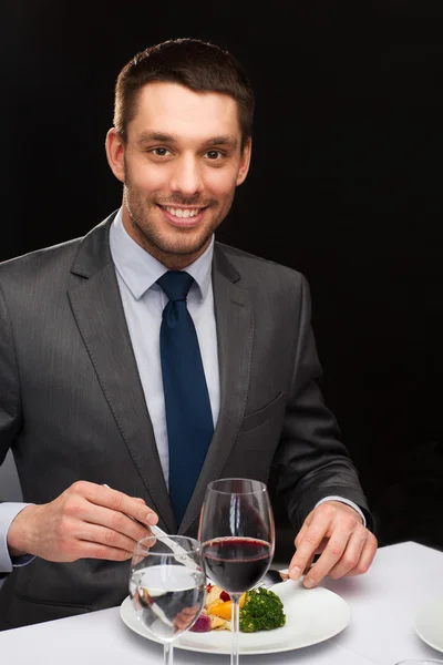 Hombre sonriente comiendo plato principal — Foto de Stock