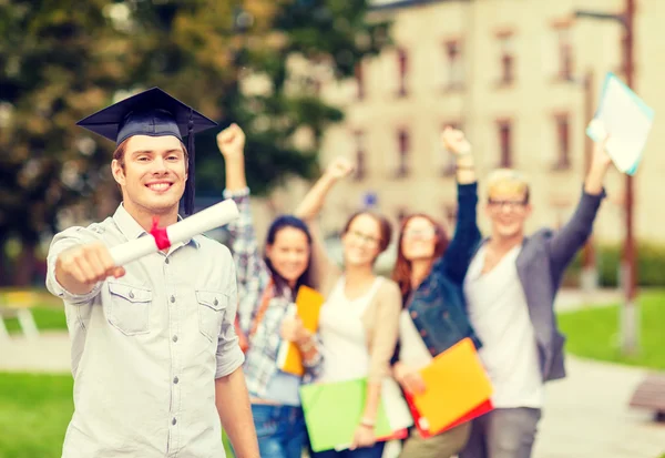 Smiling teenage boy in corner-cap with diploma — Stock Photo, Image