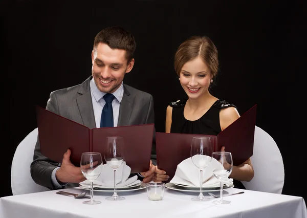 Smiling couple with menus at restaurant — Stock Photo, Image