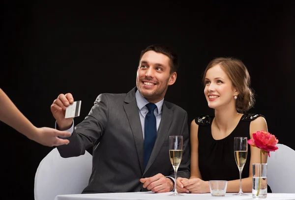 Usmívající se pár platit za večeři s kreditní kartou — Stock fotografie