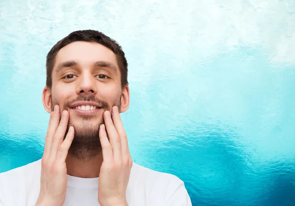 Schöner lächelnder Mann, der sein Gesicht berührt — Stockfoto