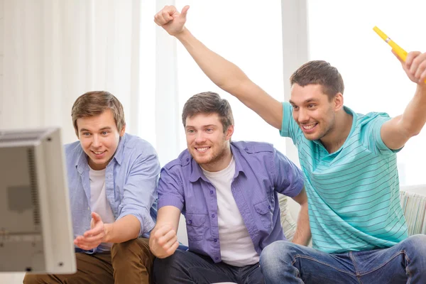 Felizes amigos do sexo masculino com vuvuzela assistindo esportes — Fotografia de Stock