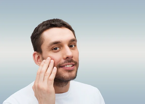 Bonito homem sorridente tocando seu rosto — Fotografia de Stock