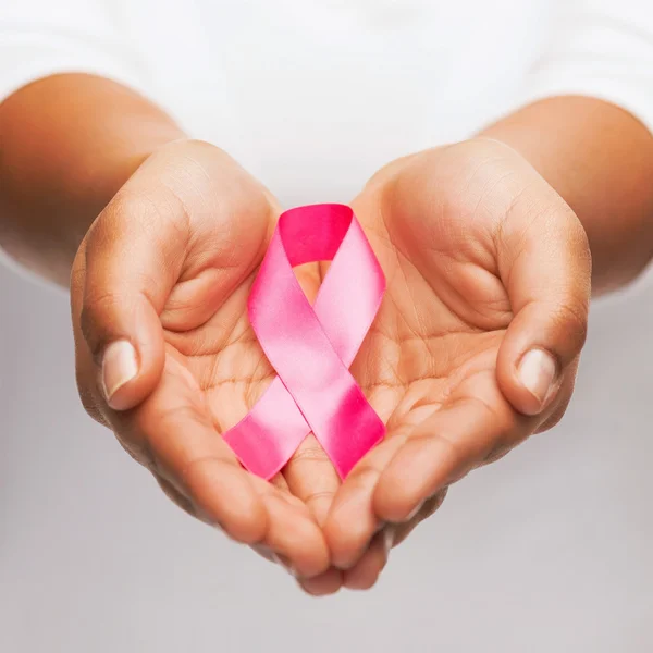 Mãos segurando fita de consciência de câncer de mama rosa — Fotografia de Stock