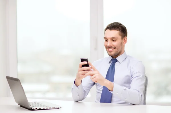 Бизнесмен с ноутбуком и смартфоном в офисе — стоковое фото