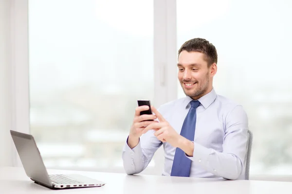 Empresario con computadora portátil y teléfono inteligente en la oficina —  Fotos de Stock