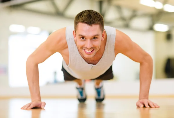 Glimlachende man doen push-ups in de sportschool — Stockfoto