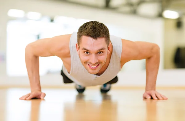 做俯卧撑在健身房里的男人微笑着 — 图库照片