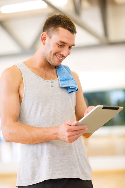 Hombre joven con tablet PC y toalla en el gimnasio — Foto de Stock