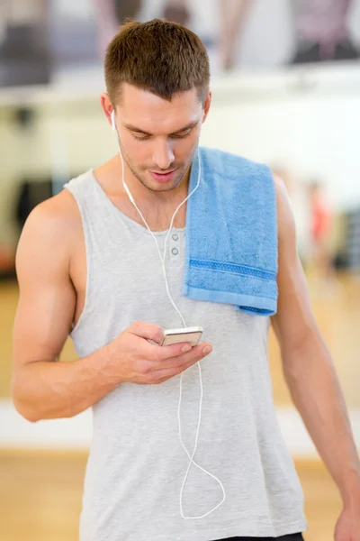 Młody człowiek z smartphone i ręcznik w siłowni — Zdjęcie stockowe