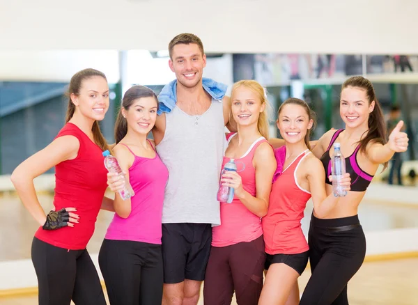 Groep van gelukkige mensen in de sportschool met flessen water — Stockfoto