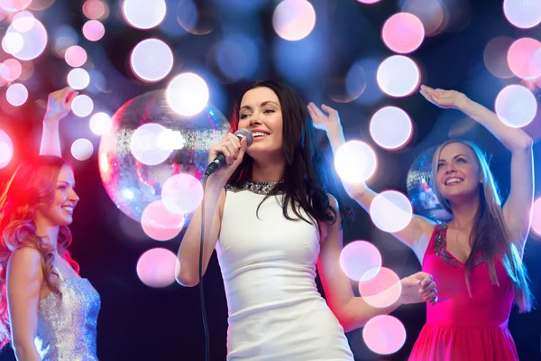 Tres mujeres sonrientes bailando y cantando karaoke — Foto de Stock