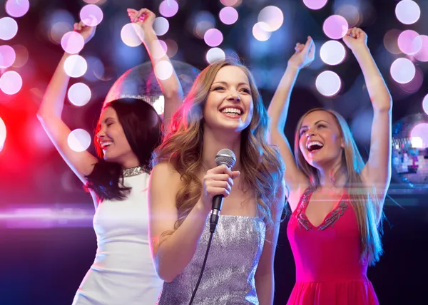 Drei lächelnde Frauen tanzen und singen Karaoke — Stockfoto