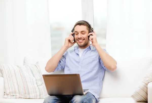 Sorrindo homem com laptop e fones de ouvido em casa — Fotografia de Stock