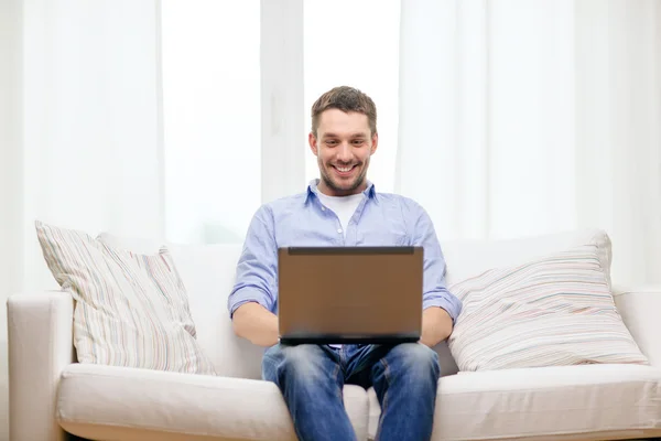 Uomo sorridente che lavora con il computer portatile a casa — Foto Stock