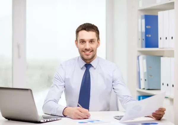 Sonriente hombre de negocios con laptop y documentos —  Fotos de Stock