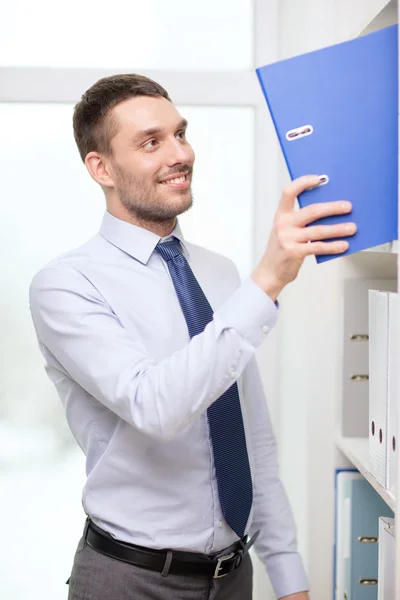 Handsome businessman picking folder at office — Stock Photo, Image