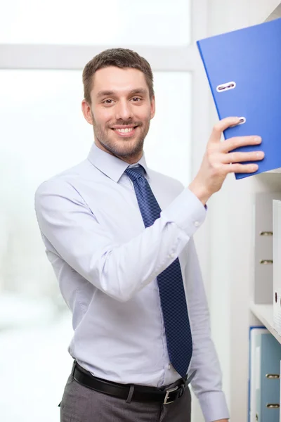 Schöner Geschäftsmann, der Ordner im Büro pflückt — Stockfoto