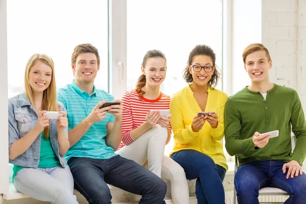 Lachende studenten met smartphone SMS op school — Stockfoto