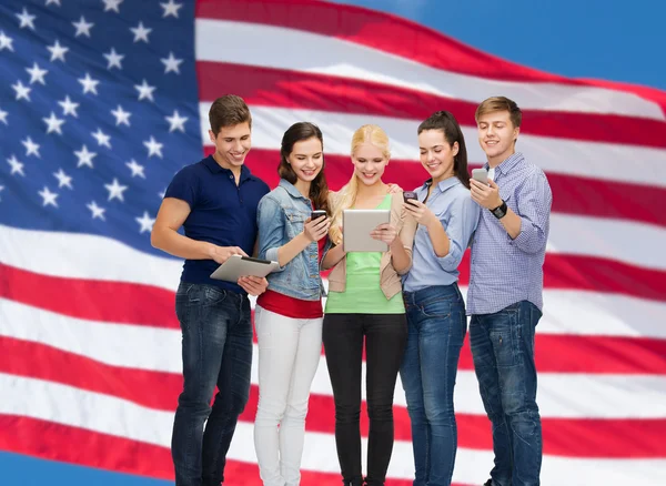 Smiling students using smartphones and tablet pc — Stock Photo, Image