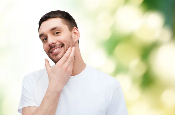 Mooie lachende man aan zijn gezicht te raken — Stockfoto