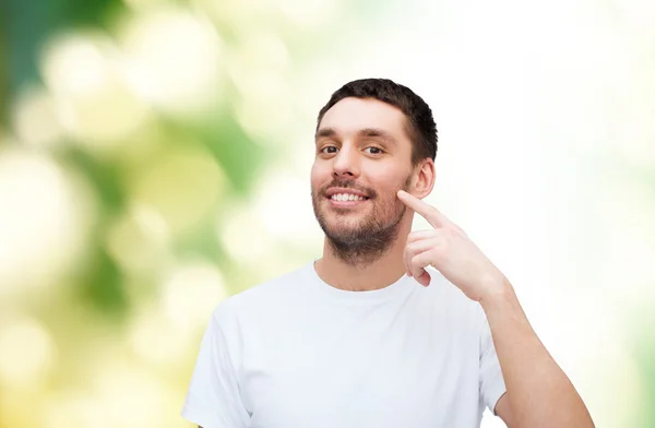 Sonriente joven guapo apuntando a la mejilla —  Fotos de Stock