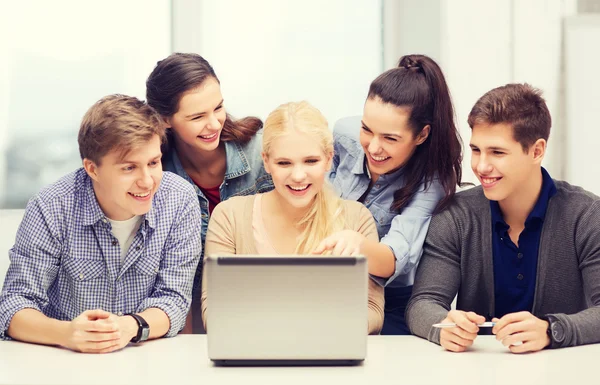 Smiling students looking at laptop at school — Stock Photo, Image