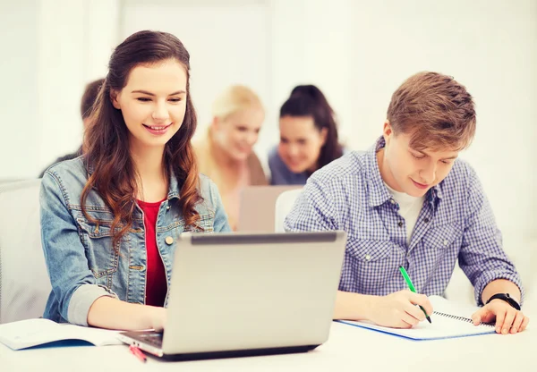 Estudantes com laptop e cadernos na escola — Fotografia de Stock