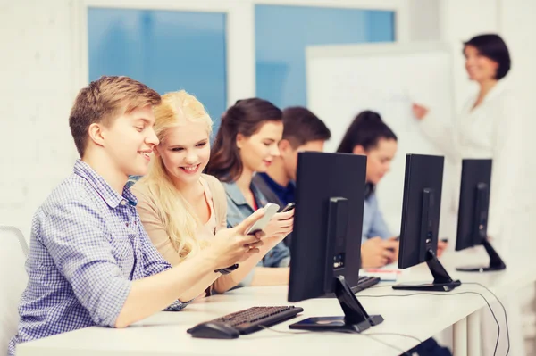 Estudiantes con monitor de computadora y smartphones — Foto de Stock