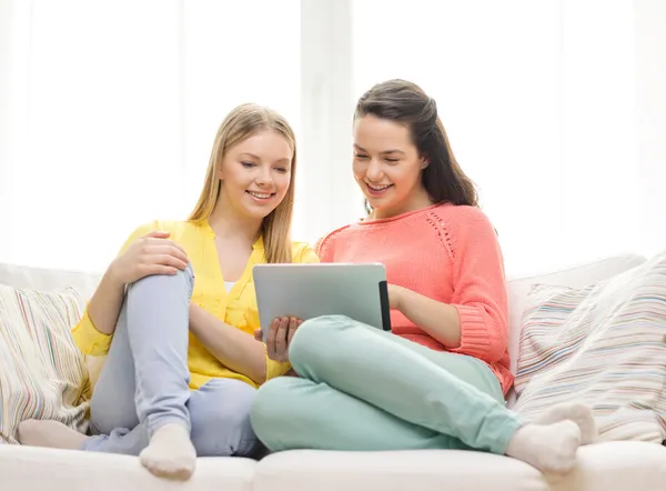 Две улыбающиеся девочки-подростка с планшетным компьютером дома — стоковое фото