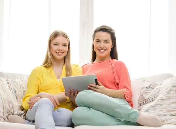 Twee glimlachend tienermeisjes met tablet pc thuis — Stockfoto