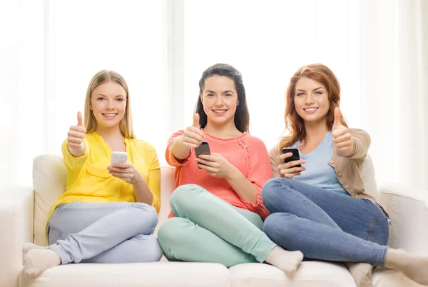 Chicas adolescentes sonrientes con teléfonos inteligentes en casa —  Fotos de Stock